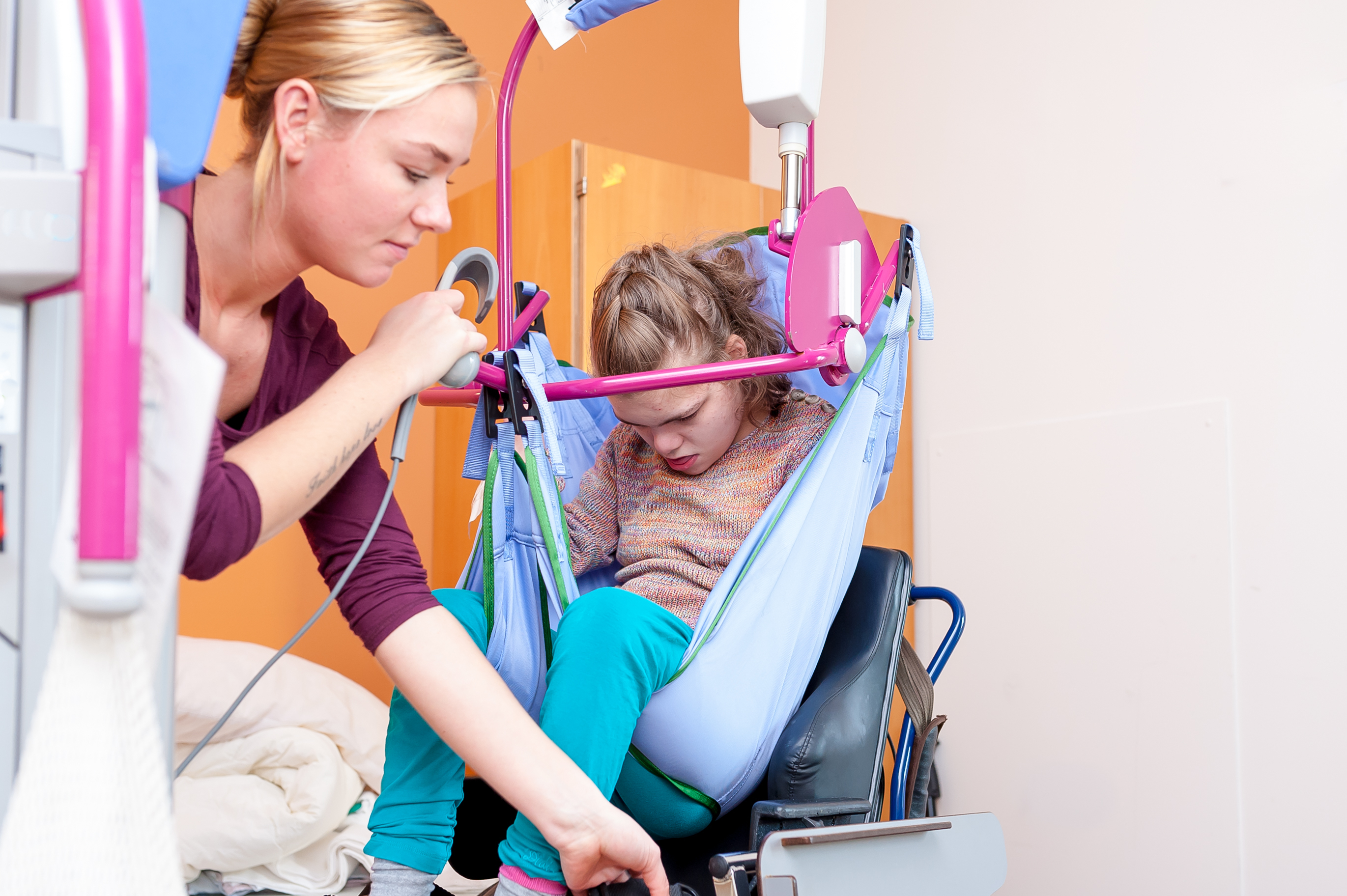 Caregiver Assisting Child Into Wheehchair