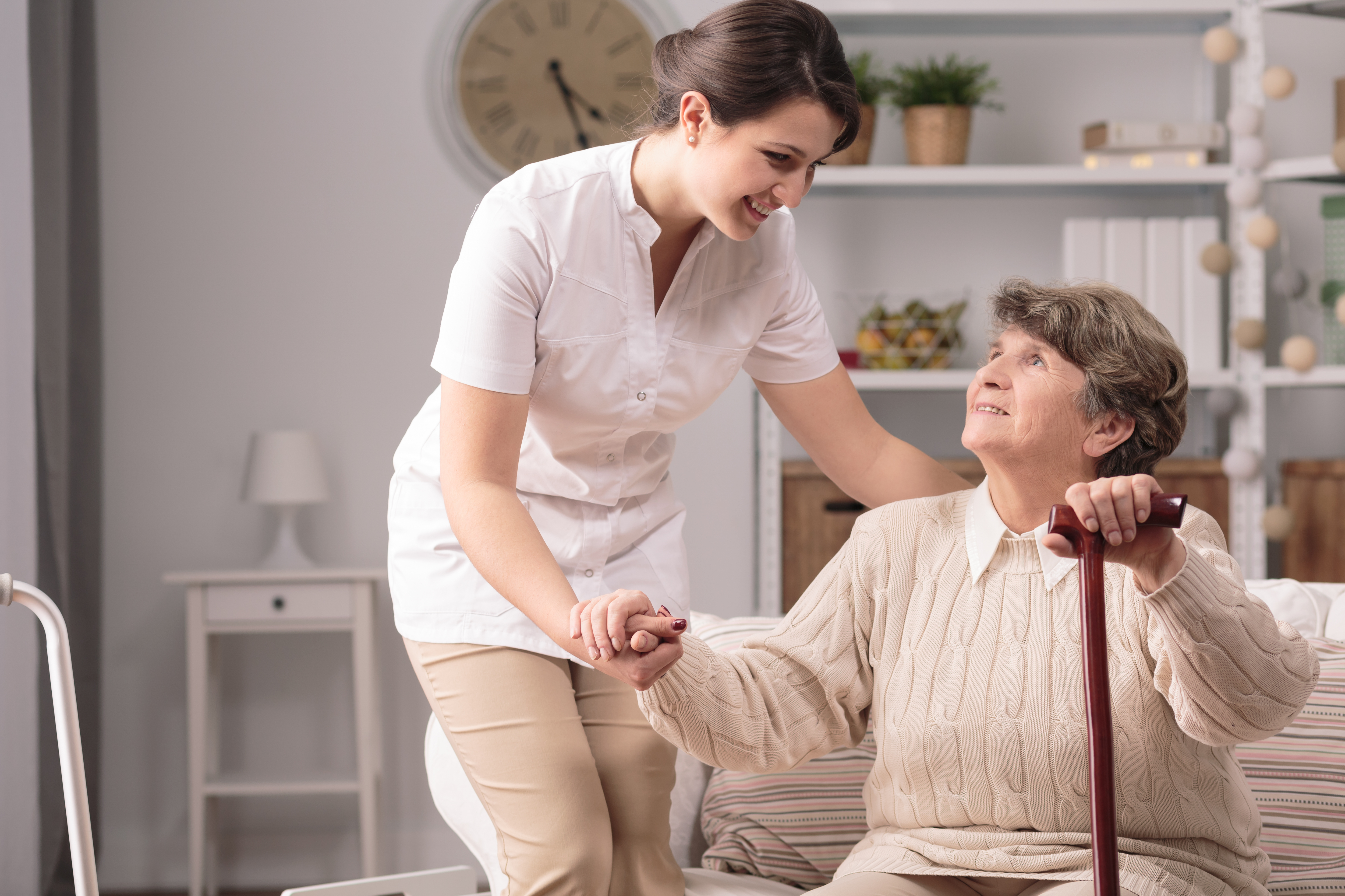 Caregiver Helping Senior Woman To Stand